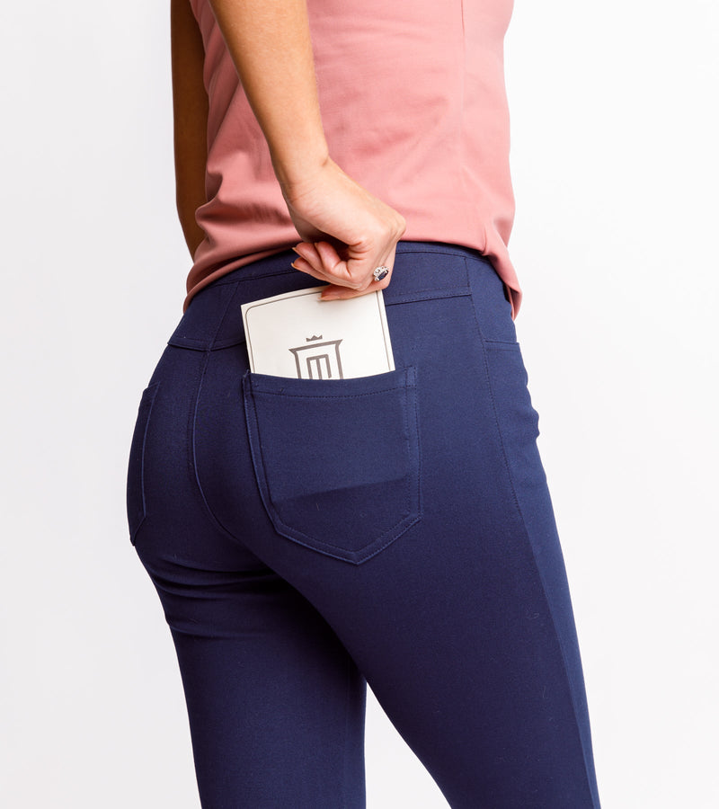 Back view of a woman wearing navy pants and a pink top, pulling out the golf card from one of the pockets.