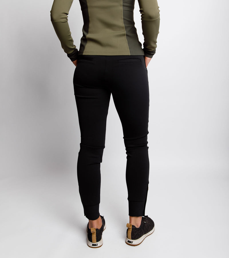  Back view of a woman wearing a black jogger and an army green pullover.