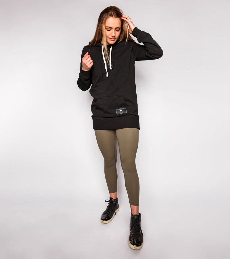 Front view of a woman wearing army green leggings and a black hoodie.