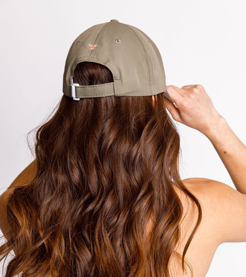 Back view of a woman wearing an army green dad hat with an adjustable snapback closure.