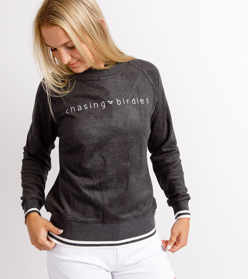 Close-up of a woman wearing a dark gray sweatshirt with white embroidery across the chest that reads "Chasing Birdies."