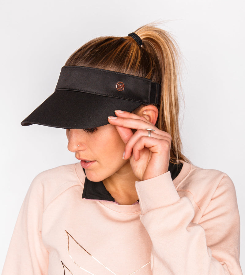 Woman holding a black visor on her head.