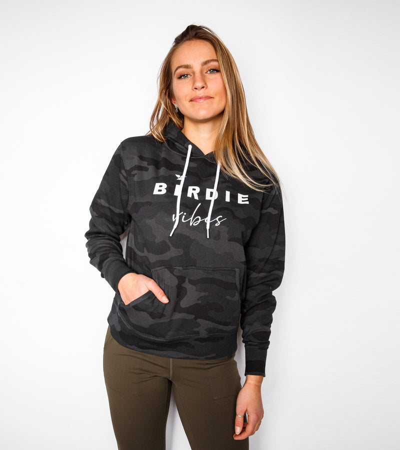 Close-up front view of a woman wearing a sleek black storm camo design with white graphics that read "BIRDIE VIBES".