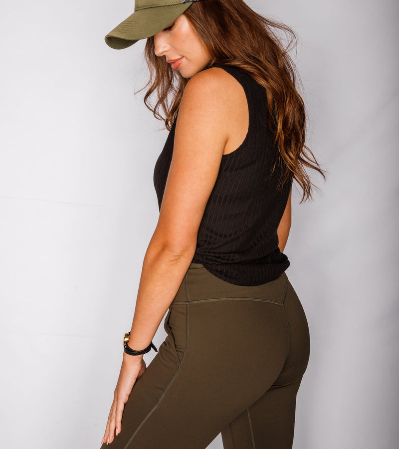 Side view of a woman wearing army green joggers and a black T-shirt.