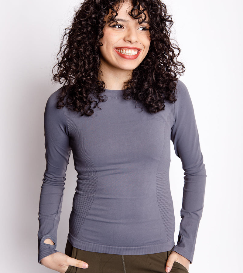 Smiling woman wearing a long-sleeve gray compression top.