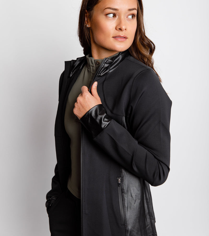 Close-up front view of a woman wearing a black jacket with a full front zip and side-bonded zipper pockets.